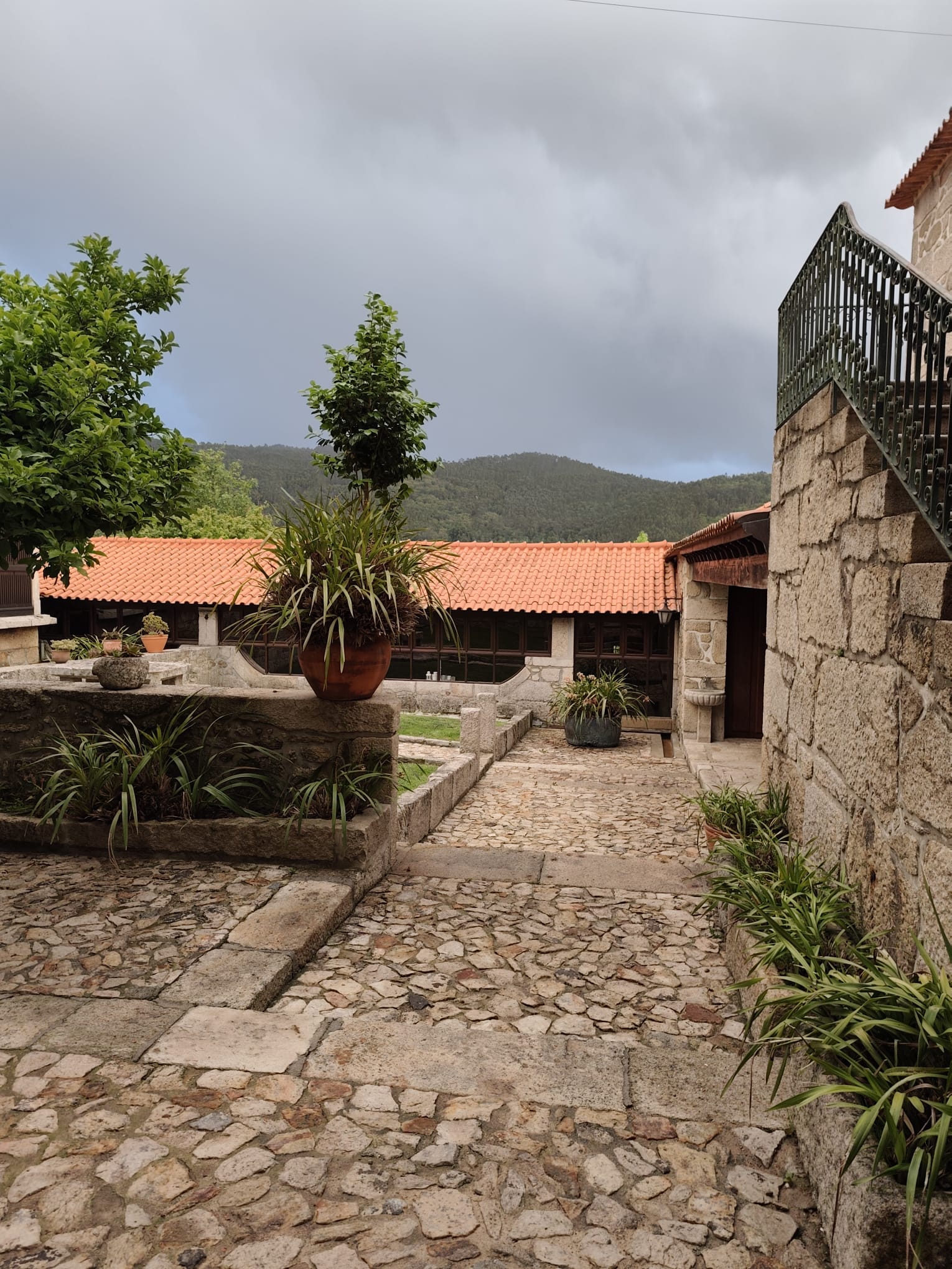 Exterior da Quinta do Coelho — pátio de pedra com jardins e serras ao fundo
