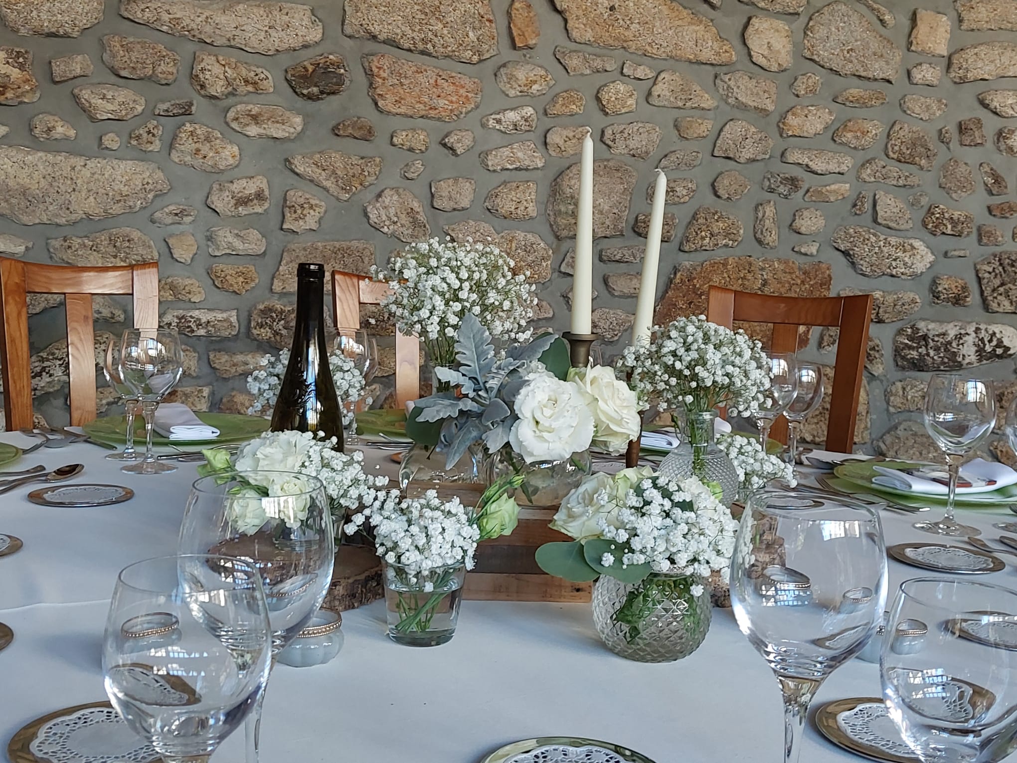 Decoração de mesa elegante com flores brancas e parede de pedra
