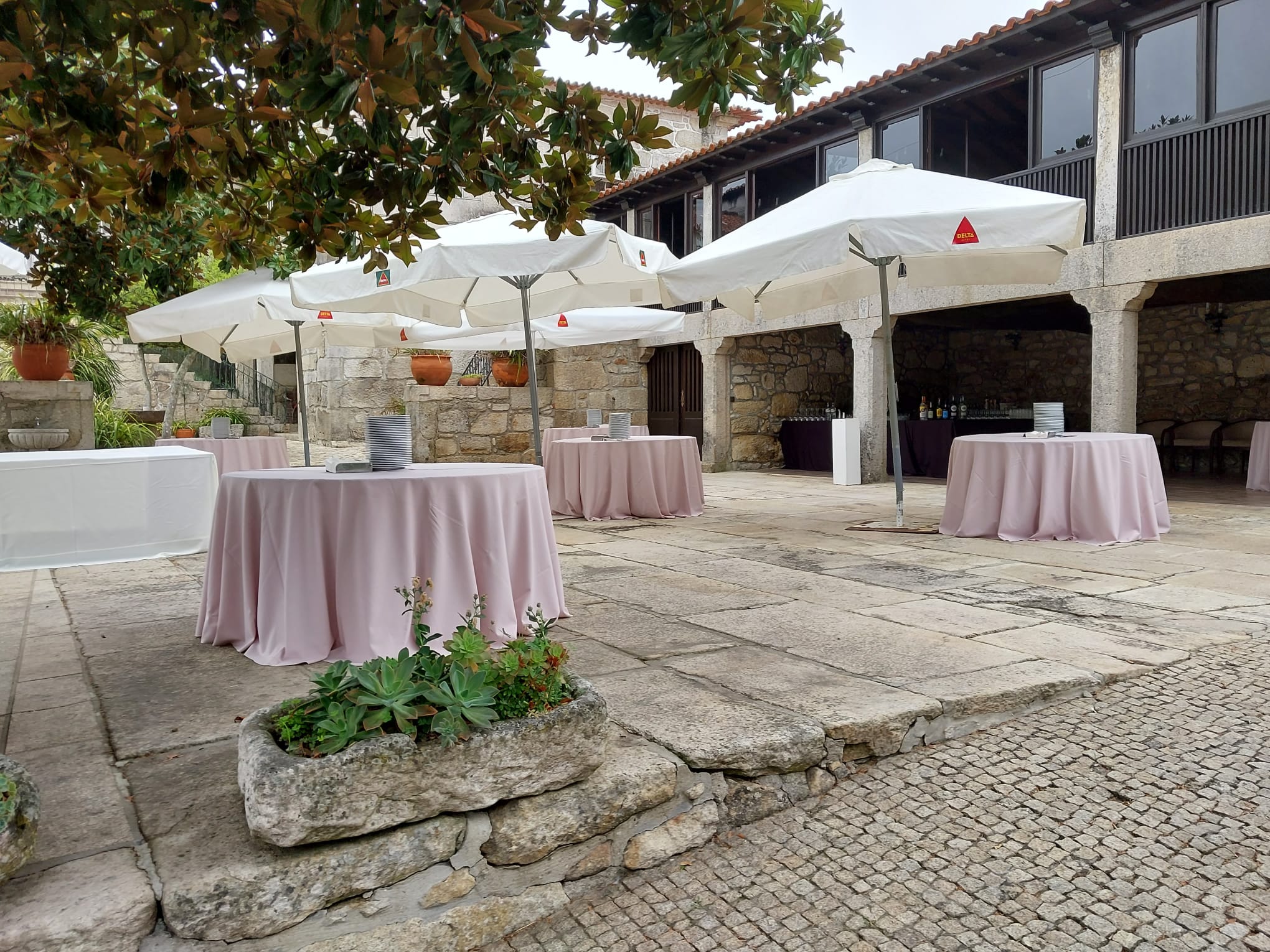 Pátio exterior da quinta com mesas e chapéus de sol